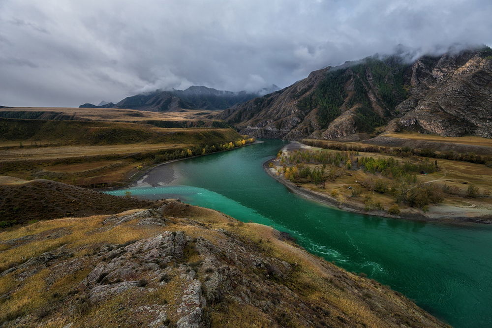 Обои для рабочего стола Горная река с лазурным отливом воды на фоне пасмурного неба
