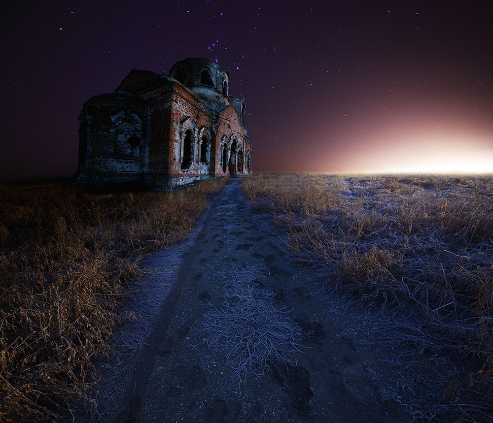 Обои для рабочего стола Старая, заброшенная, кирпичная церковь, стоящая в поле, покрытом тонким слоем инея с проходящей мимо нее дорогой на фоне звездного, ночного неба