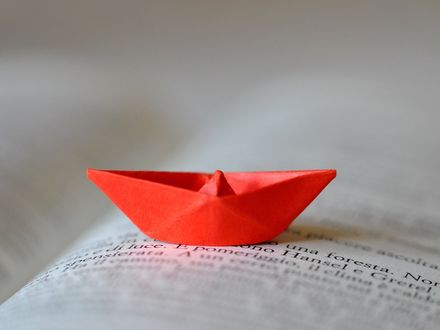 Обои на рабочий стол Красный бумажный кораблик на страницах раскрытой книги