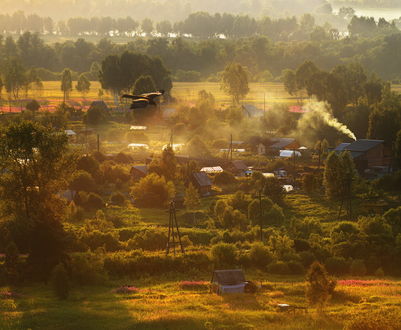 Обои на рабочий стол Утренний рассвет над небольшим поселком с деревянными домами, теплицами в огородах в окружении деревьев, идущего из трубы дыма, парящей в воздухе птицы
