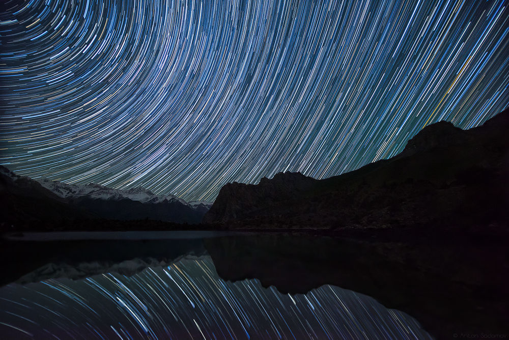 Обои для рабочего стола Яркие звездные треки на ночном небе отразились в водной поверхности горного озера