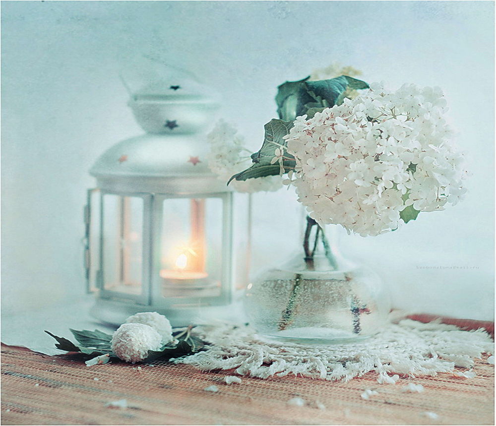 Обои для рабочего стола Декоративный фонарь с горящей свечой, стоящий невдалеке от графина с водой и букетом белых цветов в нем, автор svoboda