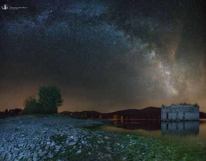 Обои на рабочий стол Заброшенная каменная башня, стоящая на мелководье горного озера на фоне ночного, звездного неба и Млечного пути, автор Jimmy Stoikov