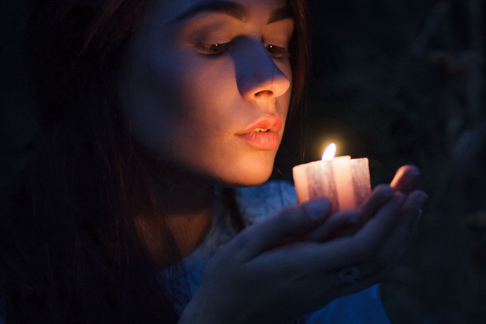 Обои для рабочего стола Темноволосая девушка держит на ладонях рук зажженную свечу