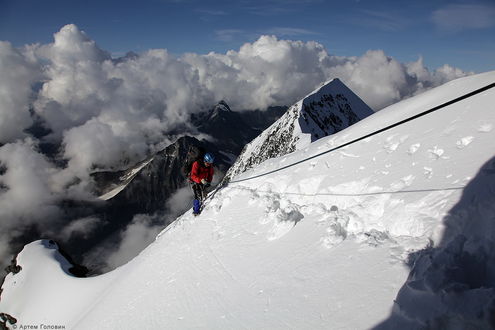 Обои на рабочий стол Мужчина-альпинист, поднимающийся по заснеженному горному массиву, держась за канат, фотограф Артем Головин