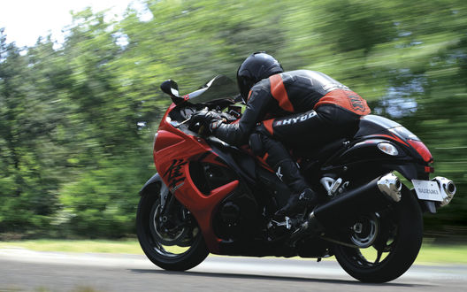 Обои на рабочий стол Мотоциклист на мотоцикле SUZUKI, мчится пригнувшись по трассе