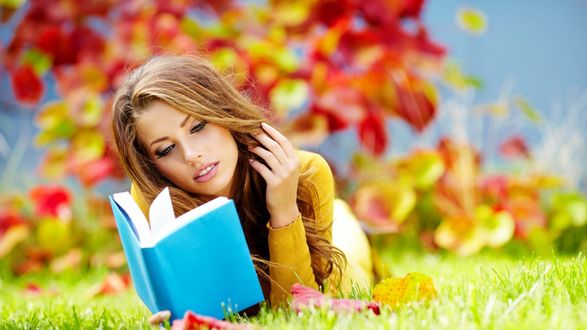 Обои на рабочий стол Девушка лежит на траве и читает книгу