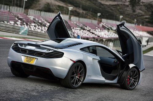 Обои на рабочий стол Суперкар McLaren MP4-12C, стоящий на стадионе