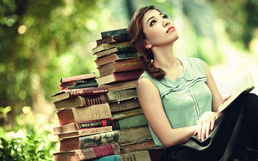 Обои на рабочий стол Девушка сидит, прислонившись к стопке книг