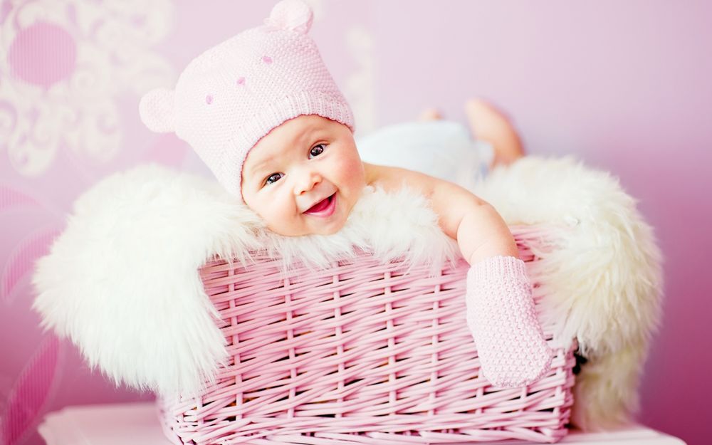 Обои для рабочего стола Младенец лежит в розовой корзине, с мягким одеялом и улыбается