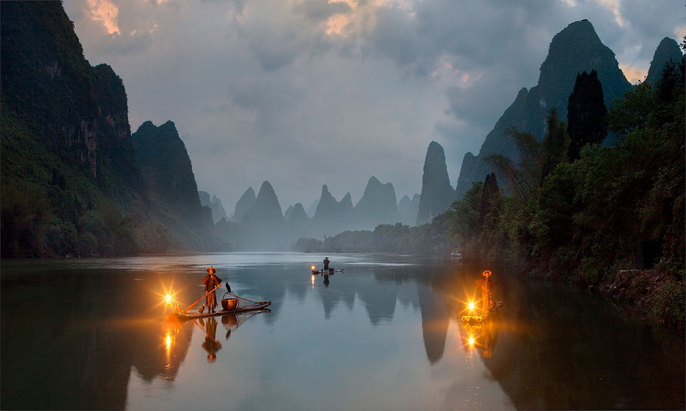 Обои для рабочего стола Китайские рыбаки, выходящие на утреннюю рыбалку на горном озере на узких, бревенчатых плотах, с корзинами для рыбного улова, сидящими бакланами, горящими на носу плотиков фонарями, Китай / China, автор Pawel Uchorczak