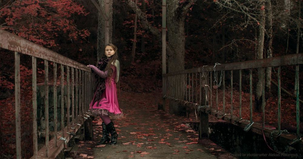 Обои для рабочего стола Темноволосая девушка в красном платье и черных сапожках, стоящая на мосту с металлическими перилами, усыпанном осенними листьями, автор Алексей Макаренок