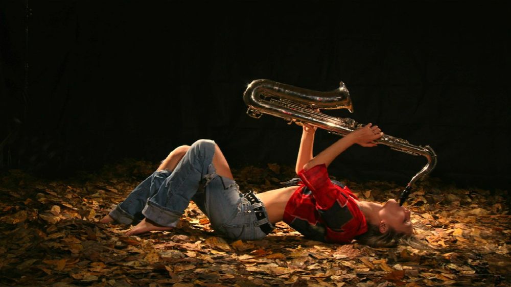 Обои для рабочего стола Девушка с саксофоном в руках лежит на осенних листьях