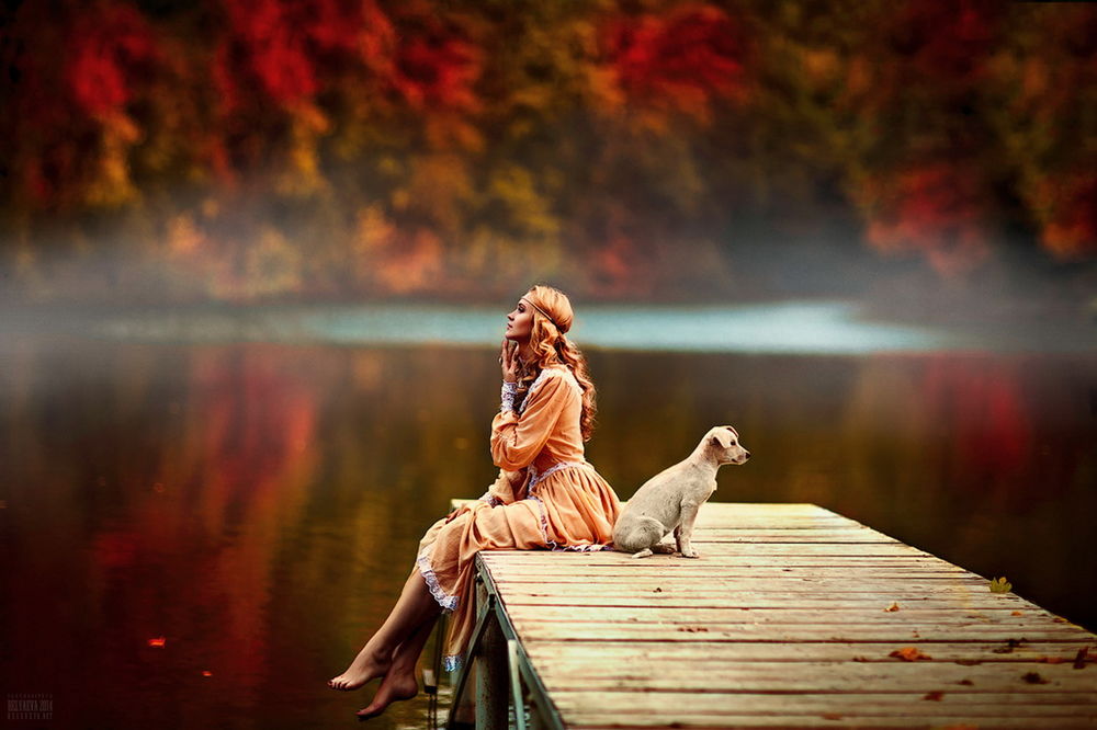 Обои для рабочего стола Рыжеволосая, босоногая девушка, сидящая на деревянном мостике с осенними листьями, расположенном у берега озера, рядом с ней сидит с домашняя собака, автор Светлана Беляева