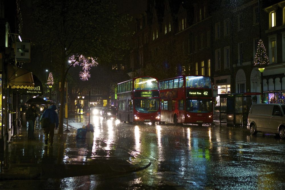 Обои для рабочего стола Двухэтажные автобусы, автомобили и спешащие прохожие с зонтиками в руках, идущие по ночным улицам дождливого Лондона, Англия / London, England