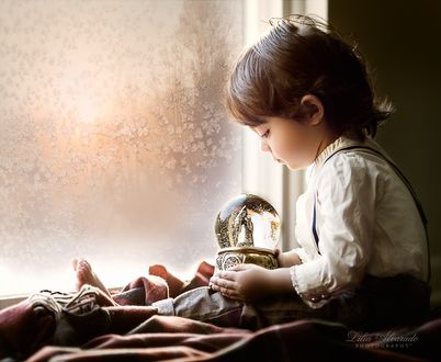 Обои на рабочий стол Маленький мальчик сидит у окна с елочной игрушкой, ву Lilia Alvarado