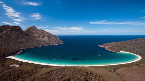 Обои на рабочий стол Морская бухта с лазурным оттенком воды, плавающими яхтами, окруженная горами на фоне синего неба и незначительной облачности