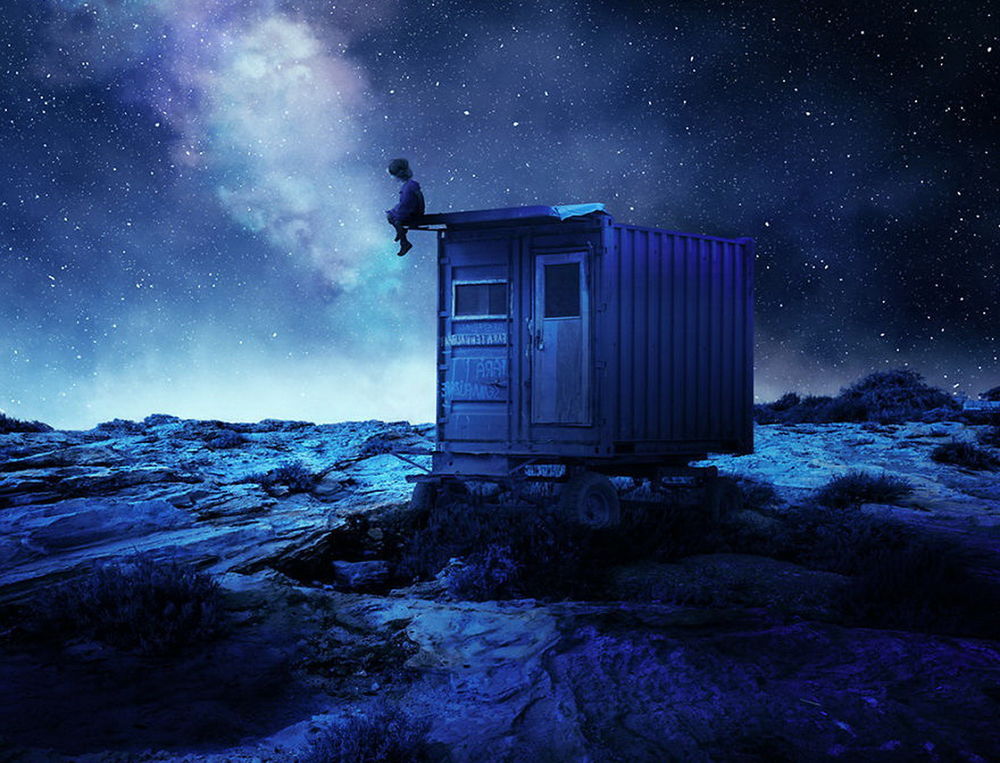 Обои для рабочего стола Мальчик, сидящий на деревянном, заброшенном домике с автомобильными колесами, стоящим на горном плато, любуется ночным, звездным небом с красивым Млечным путем, автор Garas Ionut