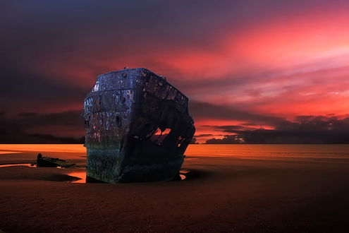 Обои на рабочий стол Ветхий, заброшенный остов корабля, стоящий на песчаном берегу моря на фоне багряного заката на вечернем небосклоне, автор Slawomir Majehrzak