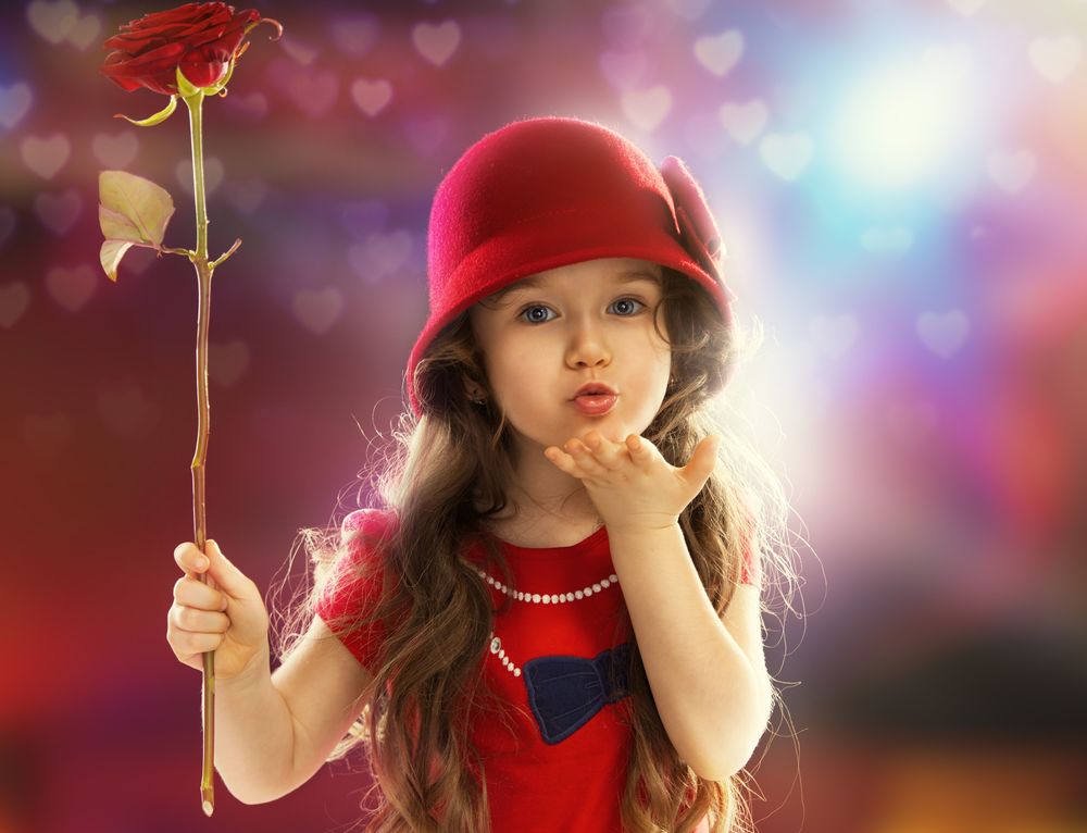 Обои для рабочего стола Девочка держит в руке красную розу и посылает кому-то воздушный поцелуй