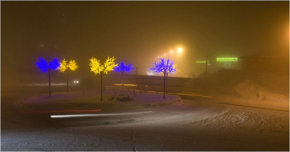 Обои для рабочего стола Деревья, покрытые праздничной, новогодней гирляндой, стоящие у заснеженной дороги на фоне ночного небосклона, окутанного густым туманом, автор Владимир