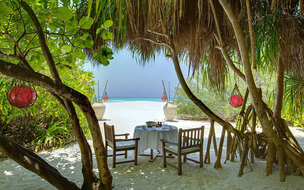 Обои для рабочего стола Столик на двоих для романтического ужина накрыт под сенью пальм на морском побережье