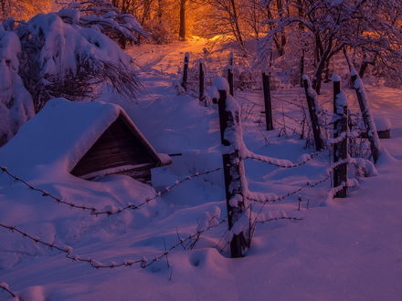 Обои на рабочий стол Небольшая деревянная избушка с толстым слоем снега на крыше, огороженная забором из колючей проволоки, автор Владимир Перепечаев