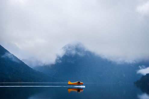 Обои на рабочий стол Самолет на воде на фоне гор в облачной дымке, фотограф Chris Burkard