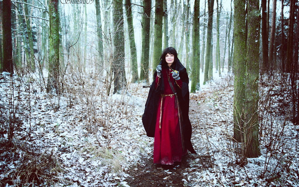 Обои для рабочего стола Черноволосая девушка в длинном, красном платье, стоящая на заснеженной тропинке в лесной роще