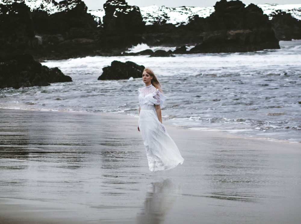Обои на рабочий стол Светловолосая девушка в длинном белом платье стоящая на песчаном берегу