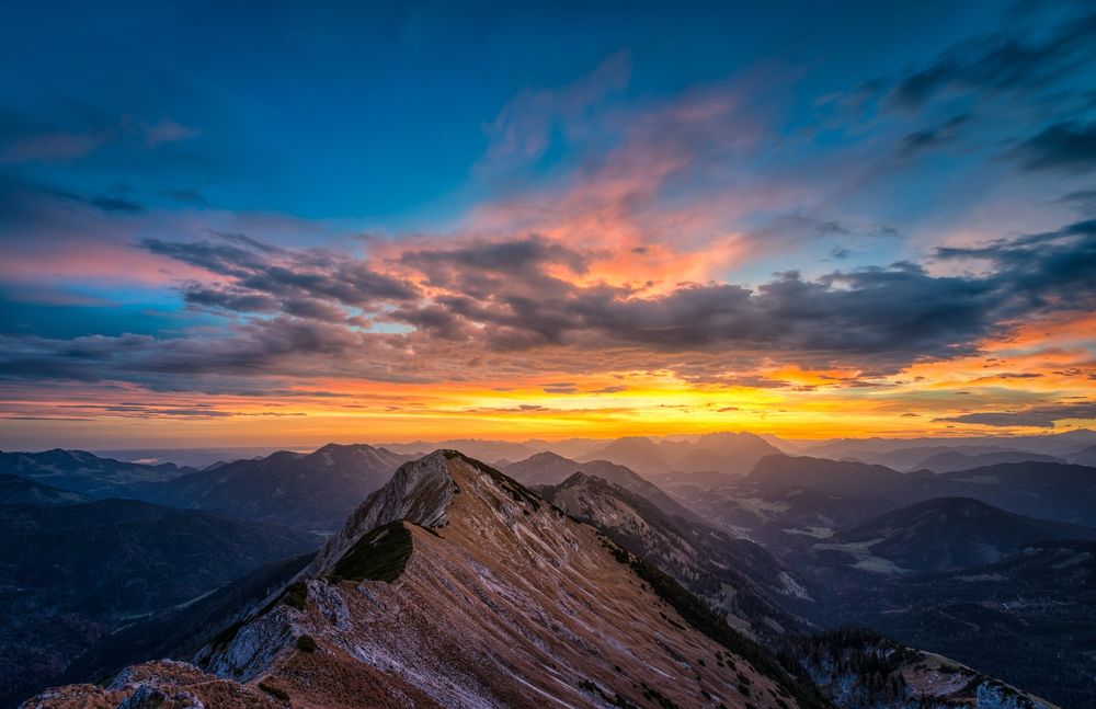 Обои для рабочего стола Восход солнца на утреннем, пасмурном небосклоне над горным образованием с заснеженными вершинами гор