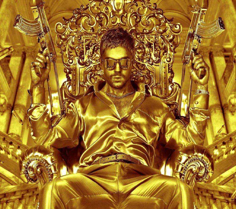 Обои для рабочего стола Актер Доминик Купер / Dominic Cooper сидит на золотом кресле, в золотом зале, с золотыми автоматами в руках, в золотых очках, из кинофильма Двойник дьявола / The Devils Double