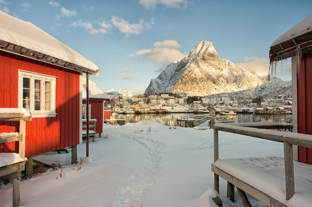 Обои для рабочего стола Рыбацкий поселок, стоящий на скалистом, заснеженном берегу морского залива на фоне синего неба с белыми, кучевыми облаками, Норвегия / Norway