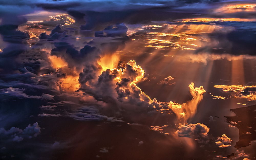Обои для рабочего стола Небо с цветными облаками сквозь толщу которых пытаются проникнуть солнечные лучи над заснеженным водоемом на земле