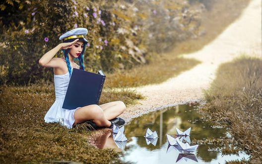 Обои на рабочий стол Девушка с книгой в руках сидит у небольшой лужи и наблюдает за плавающими в ней бумажными корабликами