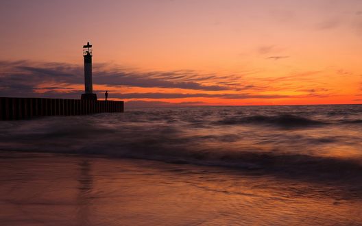 Обои на рабочий стол Человек стоит на пирсе возле маяка и морской прибой
