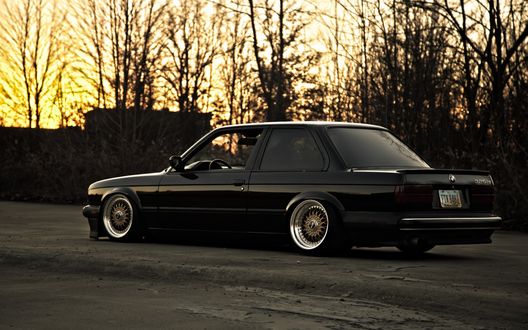 Обои на рабочий стол Черный bmw e30 325i на дороге на фоне деревьев
