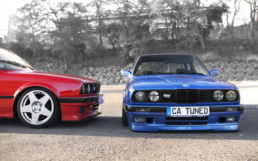 Обои на рабочий стол Синий и красный bmw e30 325i стоят на площадке на фоне деревьев