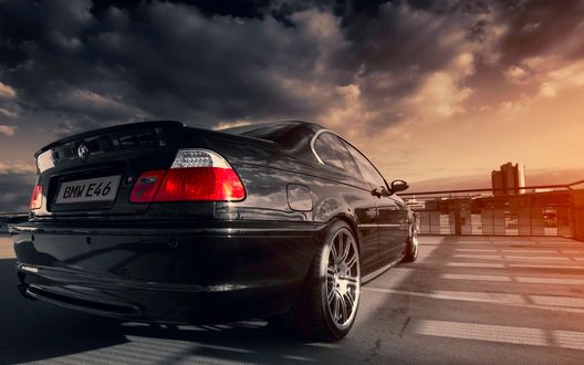 Обои на рабочий стол Черный bmw e46 328ci стоит на площадке на фоне пасмурного неба и многоэтажки