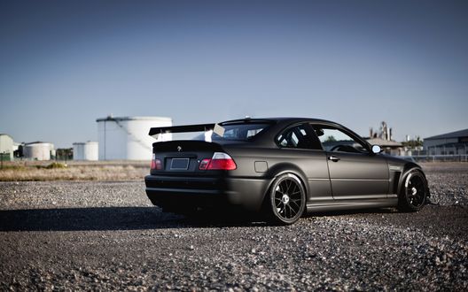 Обои на рабочий стол Черный bmw e46 m3 стоит на площадке в промзоне на фоне емкостей
