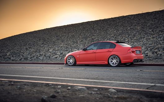 Обои на рабочий стол Красный bmw e90 335i стоит на дороге возле каменистой насыпи