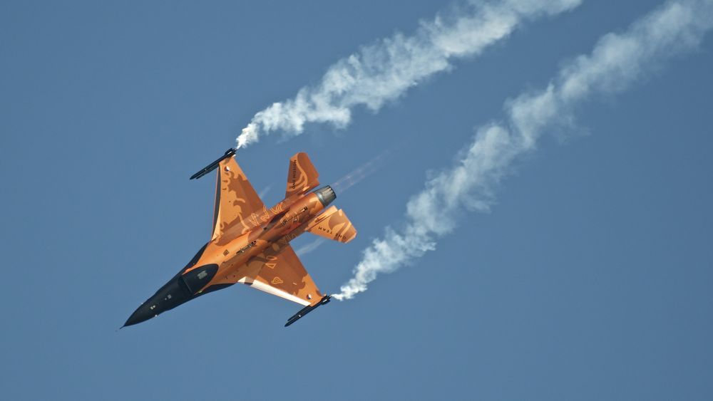 Обои для рабочего стола Голландский военный истребитель F-16 AM летит в небе, оставляя белый след от выпускаемых ракет
