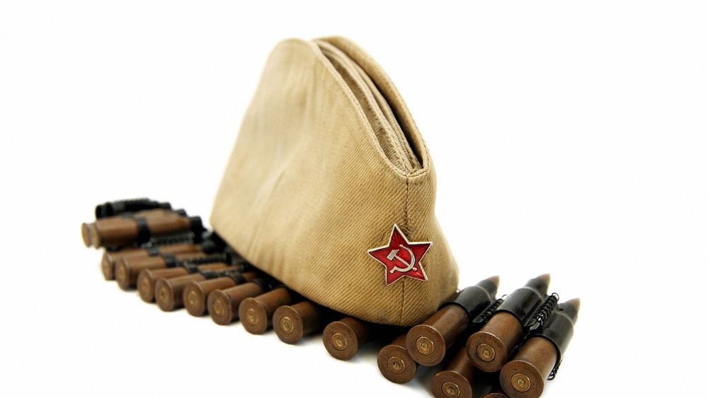 Обои для рабочего стола На пулеметной ленте с патронами лежит солдатская пилотка с красной звездой, с серпом и молотом