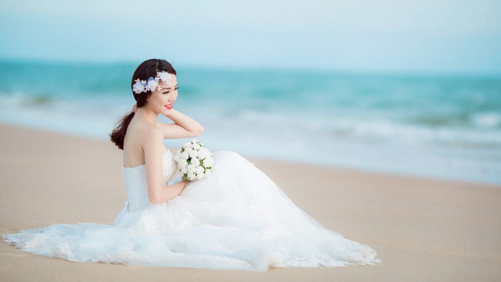 Обои для рабочего стола Невеста на побережье сидит с букетом белых цветов