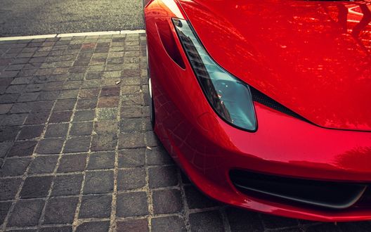 Обои на рабочий стол Фара Ferrari, стоящего на брусчатке