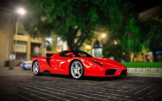 Обои на рабочий стол Ferrari на вечерней городской улице на фоне деревьев