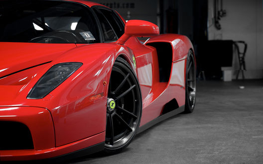 Обои на рабочий стол Красный Ferrari в боксе (вид спереди-сбоку)