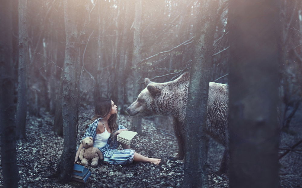 Обои для рабочего стола Девушка сидящая на земле, в лесу, смотрит на медведя стоящего перед ней