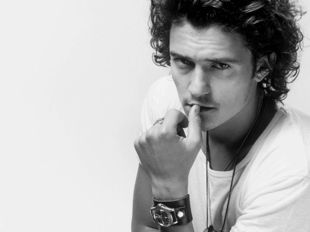 Обои для рабочего стола Британский актер Орландо Блум / Orlando Bloom, задумавшись, держит руку у рта и смотрит на нас