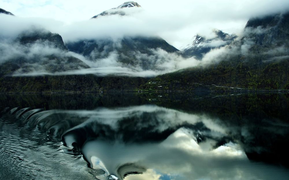 Обои для рабочего стола Волна в горном озере, в котором отражаются покрытые туманом заснеженные вершины гор, Норвегия / Norway